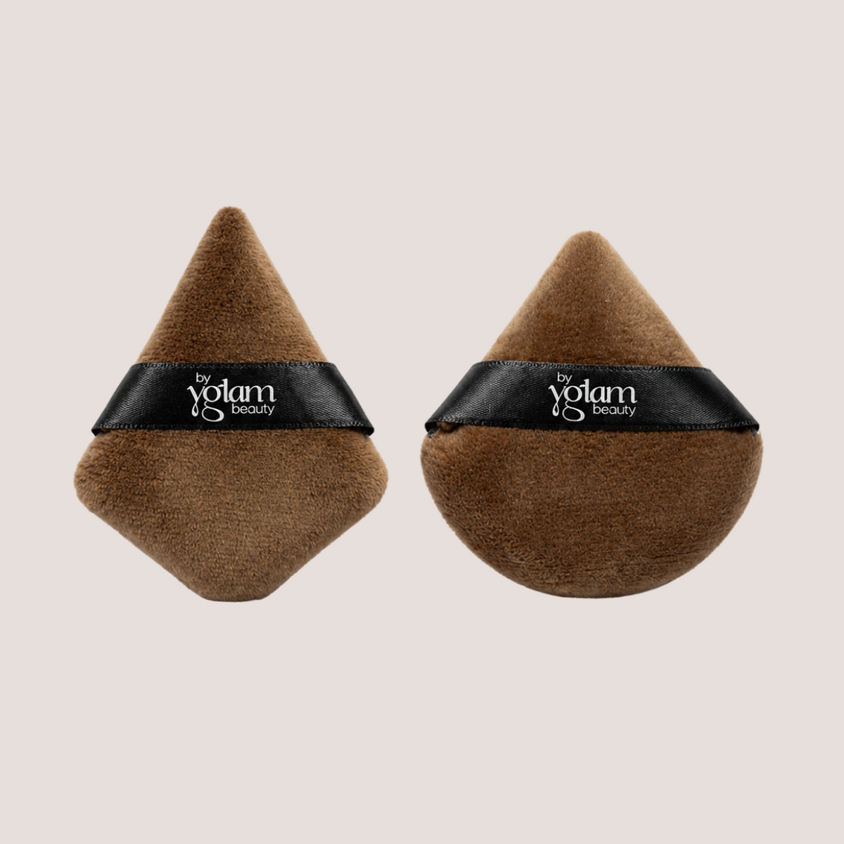 Two brown makeup sponges by By Yglam Beauty on a beige background.